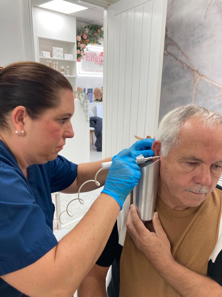 Alison performing ear wax removal by irrigation on a patient during a home visit