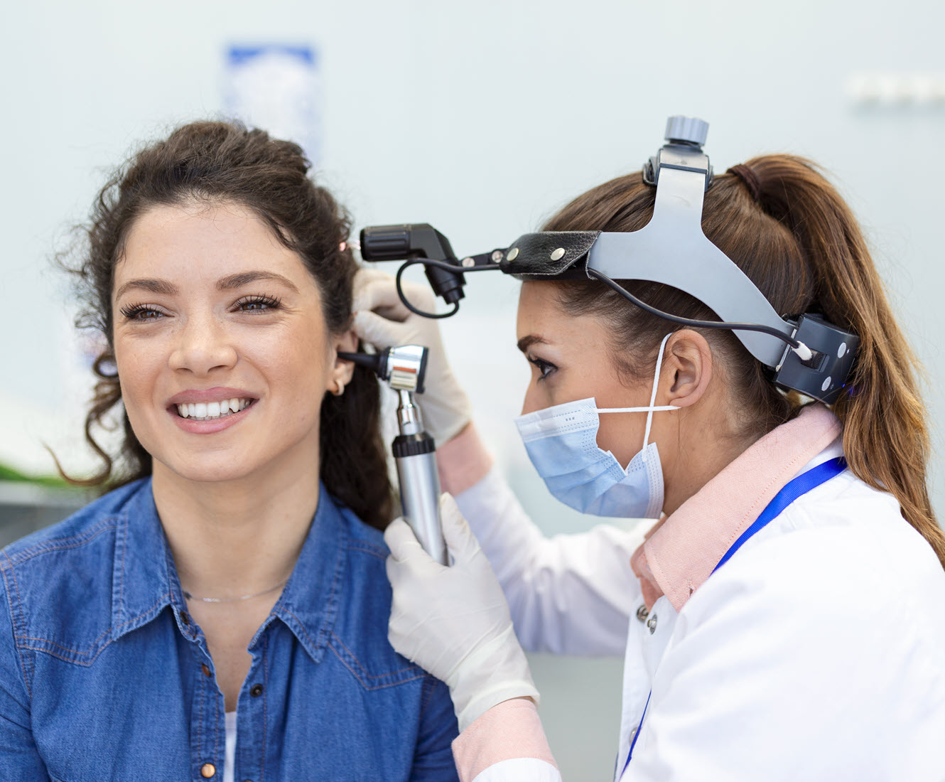 Alison examining a smiling patient's ear during a wax removal appointment